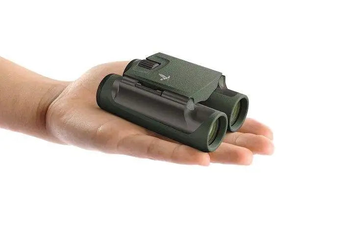 Green binoculars held in a hand against a white background